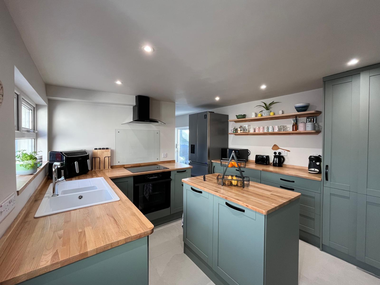 Finished kitchen fitted by A&C with green shaker units and solid timber worktops