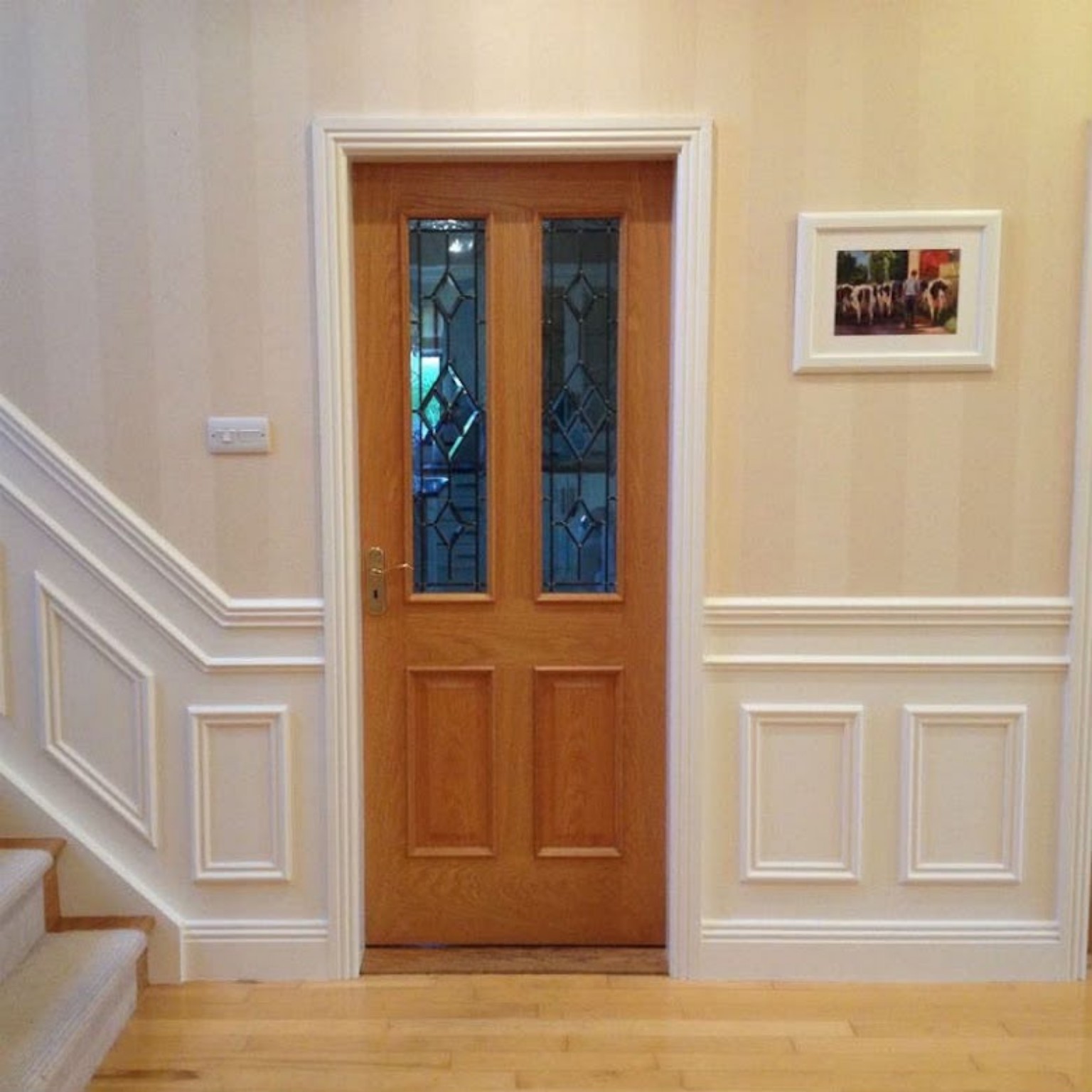 Hallway with fitted wall panelling, timber floor and hardwood door